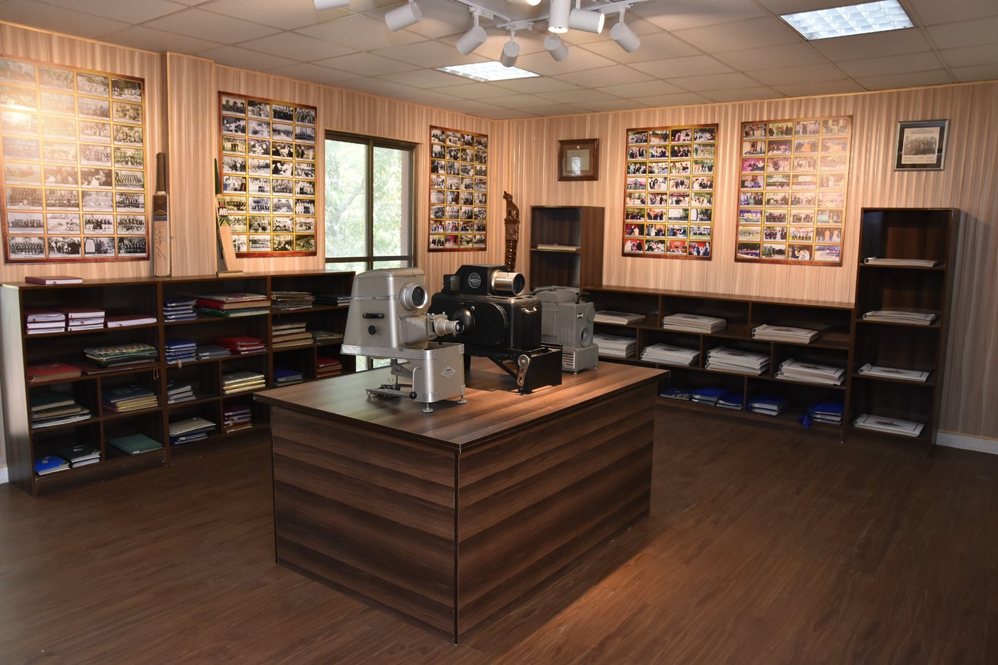 The museum room, its walls lined with mounted photographs and its shelves with bound volumes, early cameras and a projector displayed on the central case