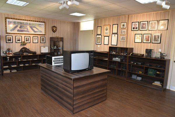 Honours boards and a gallery of framed portraits above cases holding college equipment from earlier decades